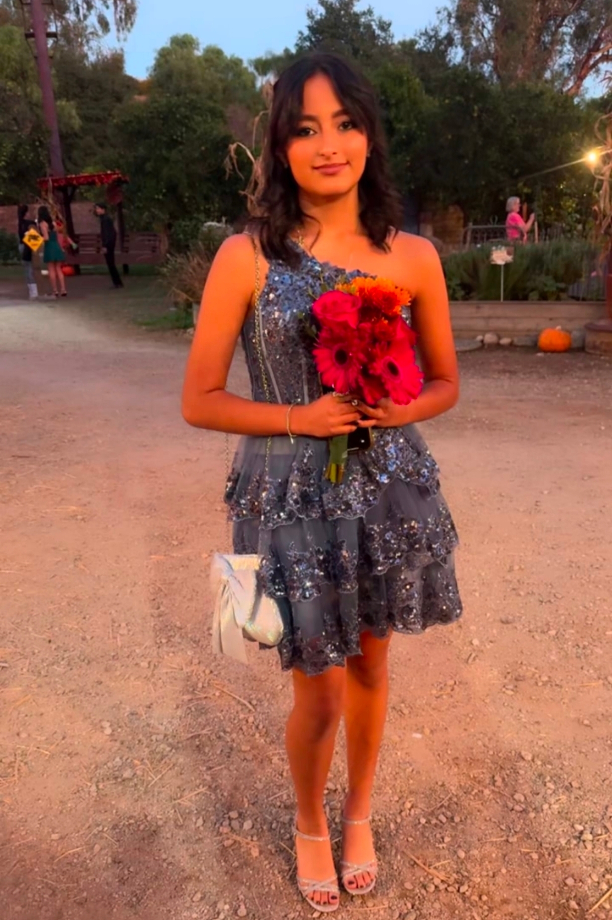 Yvanna standing in a silver dress holding a bouquet